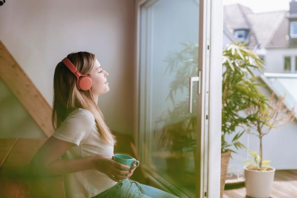 young woman relaxing at home with a cup of tea, listening music