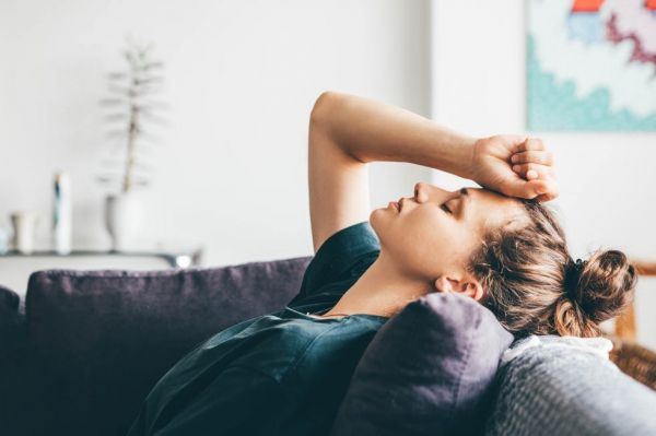 sad and depressed woman sitting on sofa at home