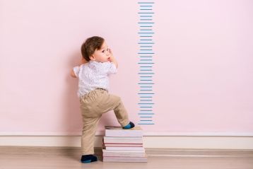 一名年幼儿童站在生长曲线表旁边