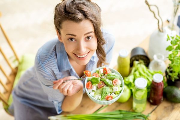 Young,And,Happy,Woman,Eating,Healthy,Salad,Sitting,On,The