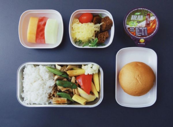东航提供的餐食包括什锦蔬菜米饭、面包卷、一杯果冻、水果片和一小份面条,配以沙拉三明治球和樱桃番茄。