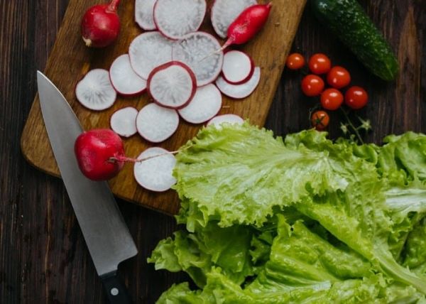 Un rábano cortado en rodajas junto a una lechuga verde