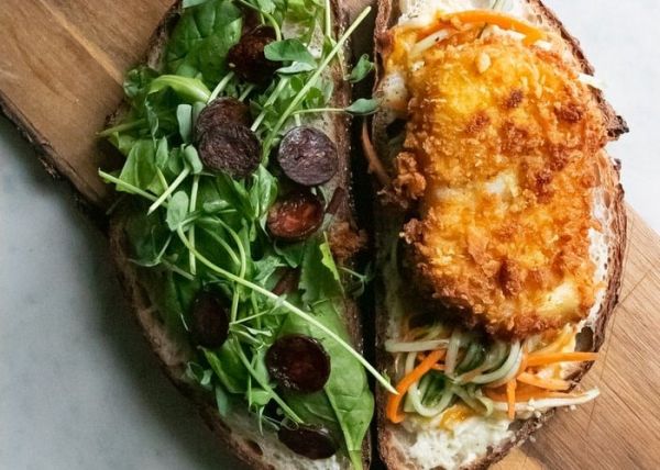 Una tapa de una tosta de pollo aderezado con piña y hojas verdes