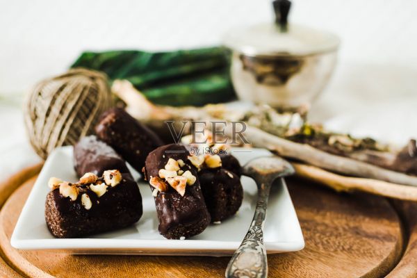 健康的生巧克力和核桃放在白色的方形盤子里。素食或減肥食品照片攝影圖片