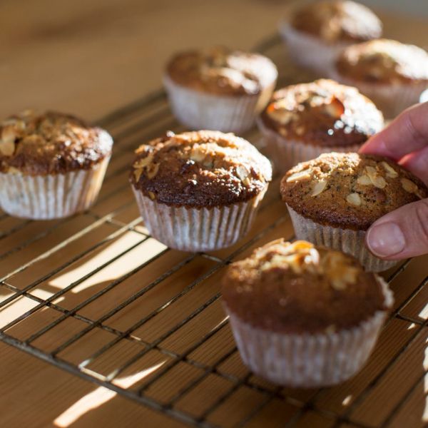 hand picking up gluten free muffins from cooling tray