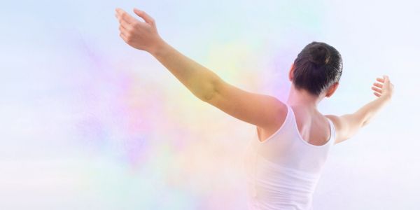 Person with outstretched arms embracing a vibrant, colorful aura symbolizing wellness, vitality, and the healing benefits of herbal teas from Sacred Plant Co.