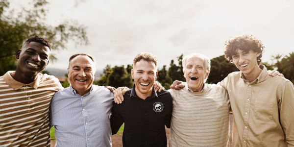 This image of a diverse group of smiling men in an outdoor setting radiates positivity, connection, and vitality.