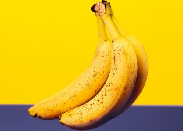 Unos cuantos plátanos amarillos en un fondo amarillo y azul