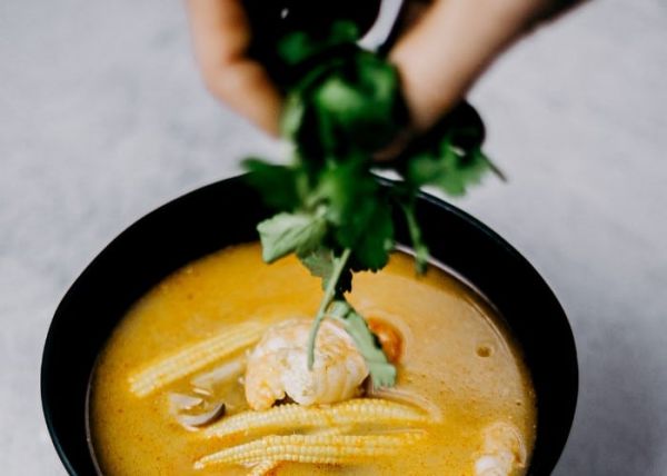 Un hombre agregando cilantro a su sopa de verduras