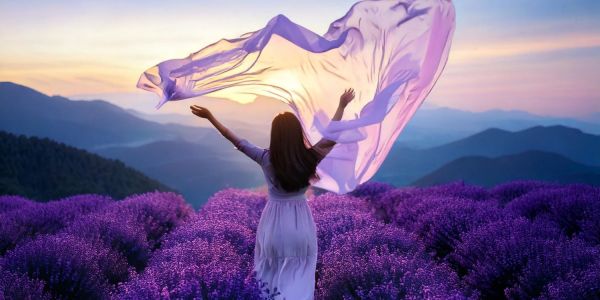 A serene and uplifting image featuring a woman standing in a vibrant lavender field at sunset, draped in flowing, translucent fabric.