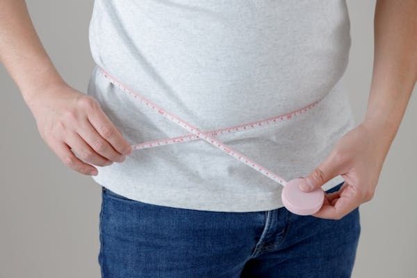 メジャーで腹部を計測するメタボ気味な男性