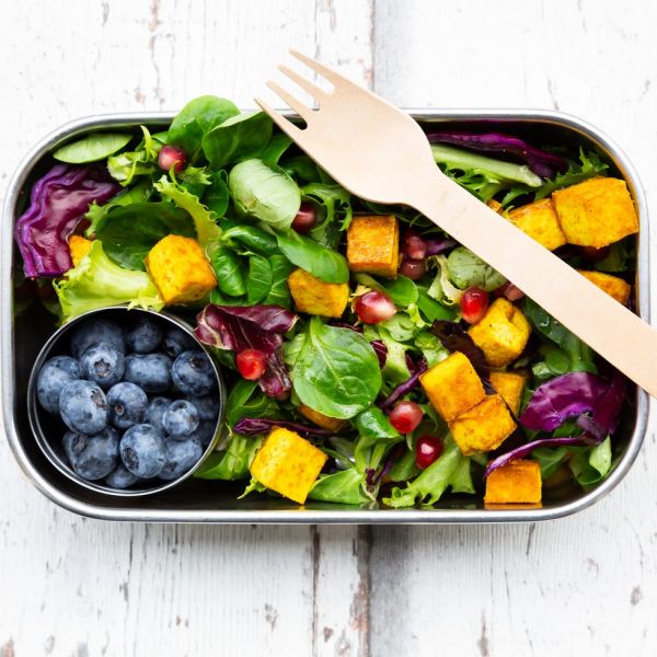 mixed salad with roasted tofu, red cabbage, pomegranate seeds, blueberries and curcuma in lunch box