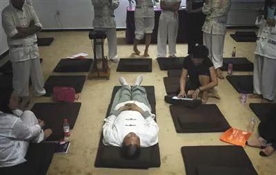 ▲辟谷老師平躺著，向?qū)W員傳授“上古能量驅(qū)寒服氣法”，圖片來(lái)自新京報(bào)網(wǎng)