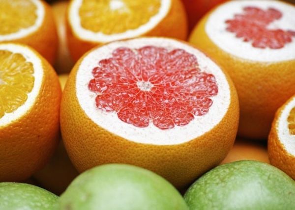 Un pomelo junto a varias naranjas