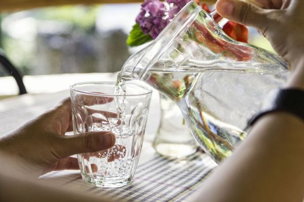 woman's hands pouring water into glass, close up