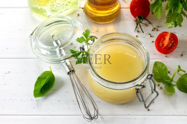 自制沙拉調(diào)味汁，配上芥末、橄欖油、檸檬汁和各種新鮮蔬菜和香草，在木制的背景上。健康飲食和排毒飲食的概念。照片攝影圖片