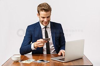 西裝革履的男士在辦公桌上使用筆記本電腦