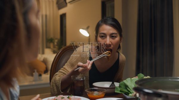 晚上，一群快乐的亚洲朋友在家里吃着火锅，聚在一起吃春节团圆饭。生活方式享受美食。照片摄影图片