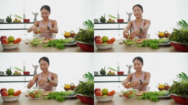 一個(gè)健康的年輕婦女在廚房里為健康餐和沙拉準(zhǔn)備水果和蔬菜