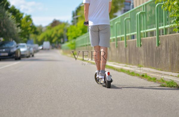 一名穿著休閑運(yùn)動服的男子騎著電動滑板車。后視圖。城市生態(tài)理念和健康生活方式照片攝影圖片