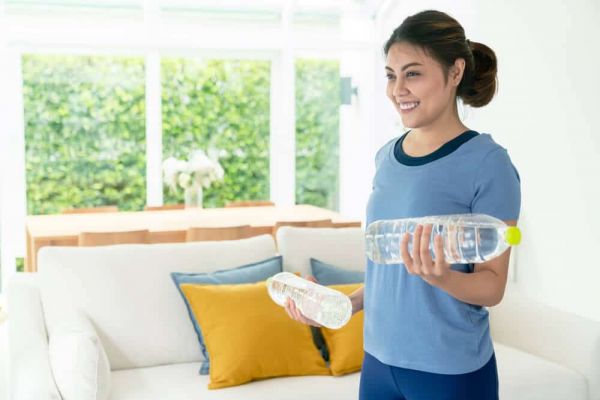 mujer con mancuernas caseras de agua