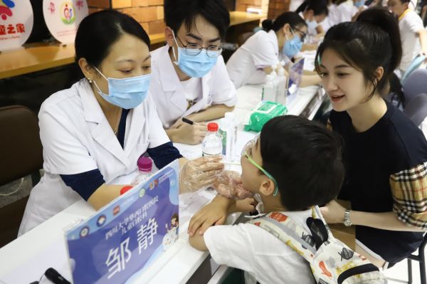 四川大学华西口腔医院儿童口腔科主任邹静教授为社区首位建立儿童口腔健康档案的小朋友做口腔检查