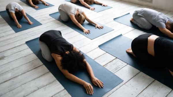 A group in child's pose in the gym.