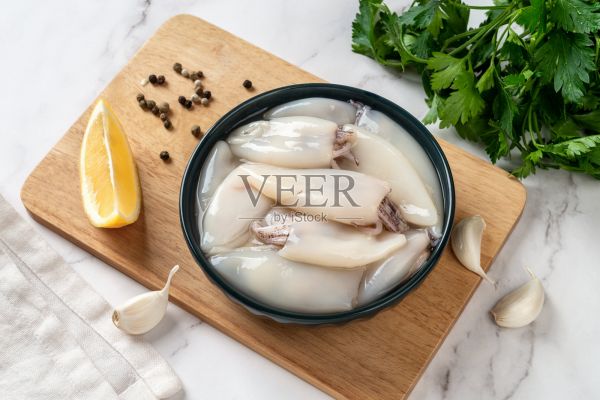 新鮮的魷魚管放在碗里。為烹飪準(zhǔn)備的小魷魚片和歐芹。生魷魚軟體作為低熱量健康飲食的配料。海鮮配方概念。照片攝影圖片
