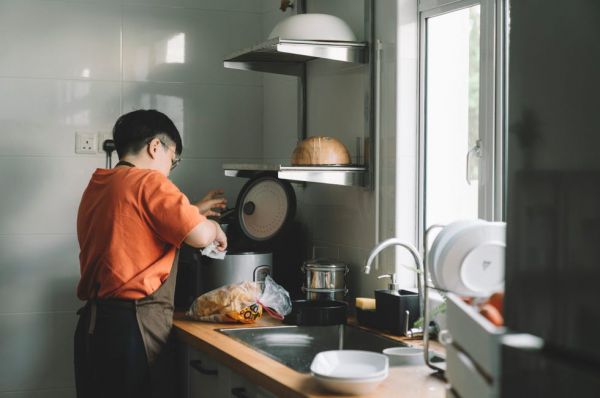 asian chinese mother cooking rice using rice cooker at kitchen
