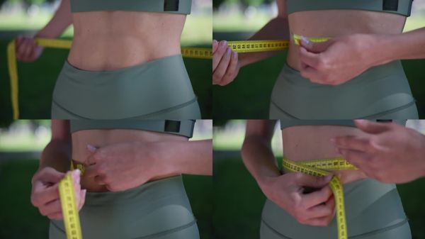 穿著運(yùn)動(dòng)服的運(yùn)動(dòng)女性。用卷尺量腰圍，在戶外因減肥而欣喜。節(jié)食，飲食失調(diào)。節(jié)食婦女測(cè)量腰圍瘦身減肥。女