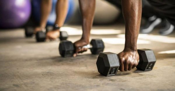 personas haciendo abdominales oblicuos con mancuernas