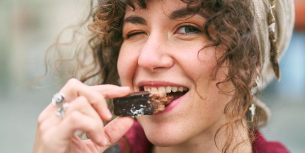 cheerful woman eating candy on street