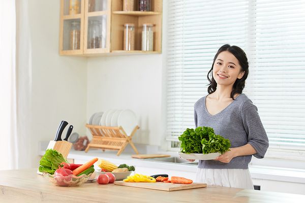 攝圖網(wǎng)_501555879_年輕女士在廚房備菜(企業(yè)商用).jpg