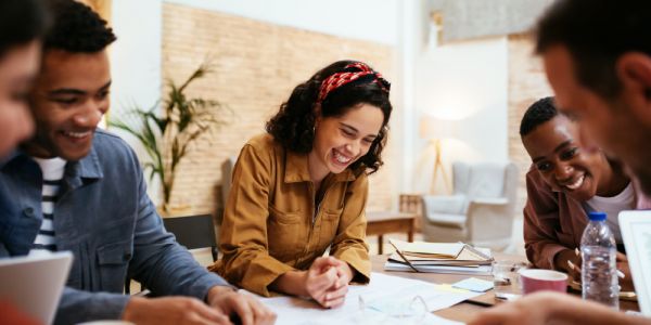 four employees gathered around a table enjoying the work they are doing