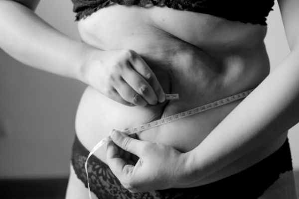 一位女士抱著乳房的灰度照片