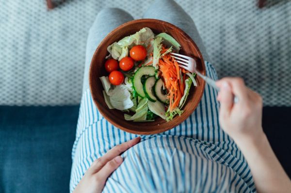 overhead shot of pregnant woman eating vegetable salad