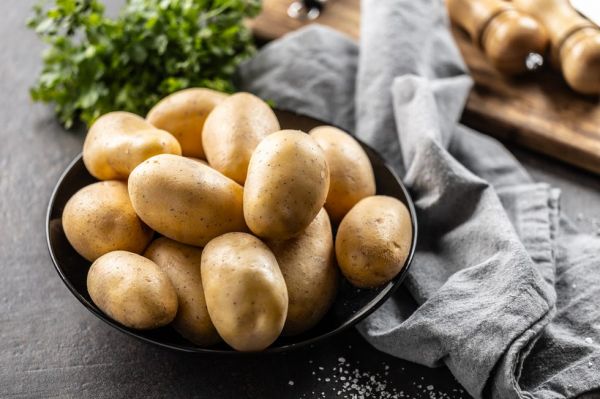 raw potatoes in a black plate on the kitchen table