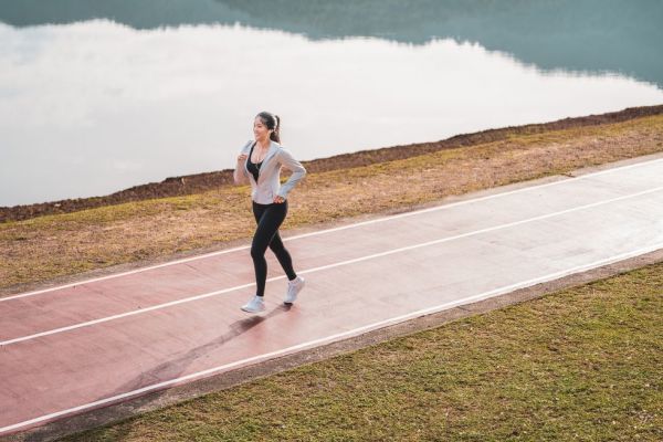 young fitness sports women runner running in the park happy athletic woman listening music on earphones while running in nature in the morning healthy fitness woman jogging outdoors