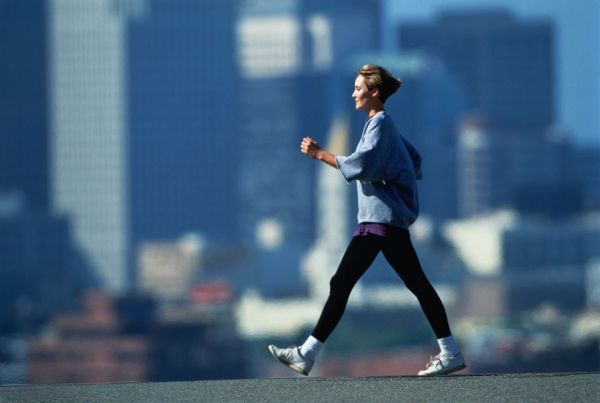 woman speed walking in fore of city skyline