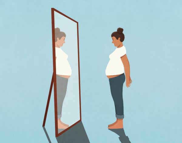 woman looking at large stomach in mirror