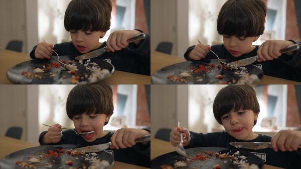 年轻男孩专注地用叉子吃着番茄酱米饭,捕捉到他对用餐的专注和享受,非常适合生活方式类视频。