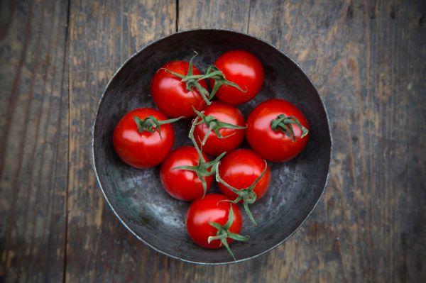 bowl with cherry tomatoes on wooden table, elevated view
