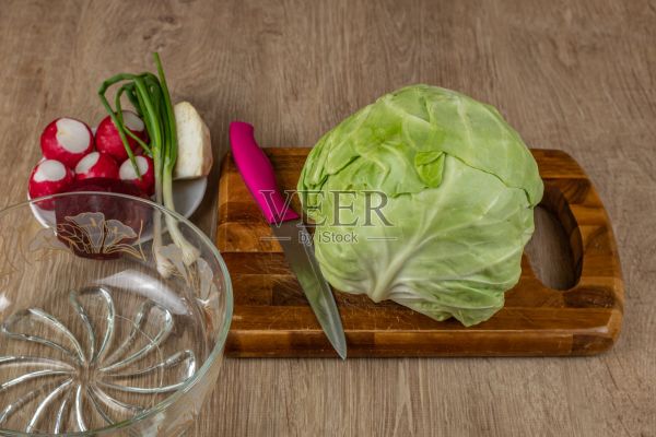 白卷心菜，红萝卜，葱，红甜菜根，芹菜根，切菜板，刀和玻璃碗制作新鲜沙拉。素食主义和生食的概念对健康有益照片摄影图片