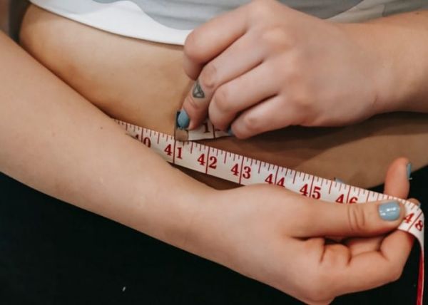 Una mujer se mide la cintura con una cinta métrica