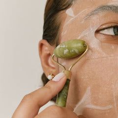 特寫鏡頭：一位女士使用玉石滾輪在臉上按摩，并敷上白色護(hù)膚面膜，以推廣整體護(hù)膚程序。