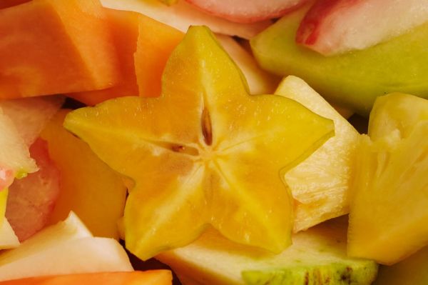 a vibrant close up of sliced tropical fruits, including watermelon, pineapple, apple, star fruit, mango, melon, papaya, and guava, beautifully mixed arranged. the bright, juicy colors and variety of textures create an enticing and refreshing visual. perfect for promoting healthy eating, tropical cuisine, fruit platters, and summer inspired content.
