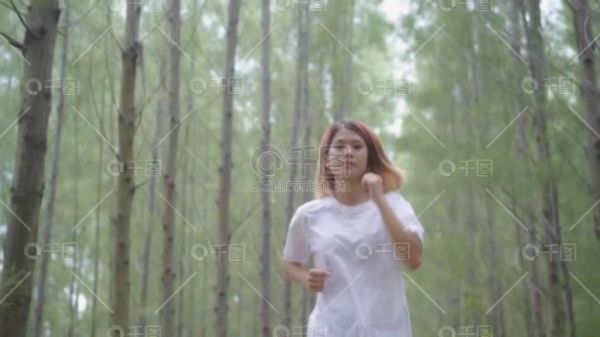慢动作-健康美丽的年轻运动运动亚洲跑步女子在运动服装跑步和慢跑森林小径上。生活方式适合和积极的妇女运动在森林概念.