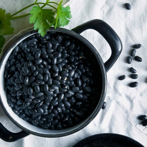 directly above shot of black beans in cooking pan on tablecloth
