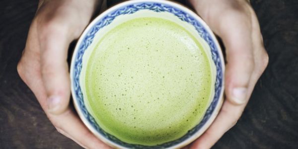 hands of man holding a cup of japanese powdered green tea