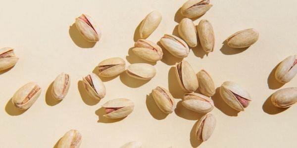 pattern of pistachio nuts on beige background healthy eating concept top view, flat lay